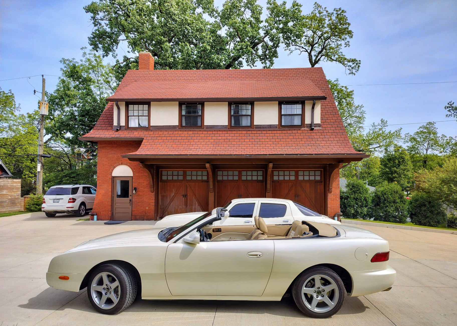 The brick carriage house behind the Castle with a classic convertible parked in front